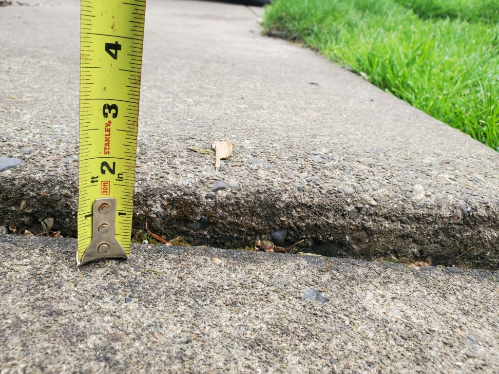 Concrete Repair Can Cost More Than You Think Uneven concrete sidewalk measured over an inch offset.