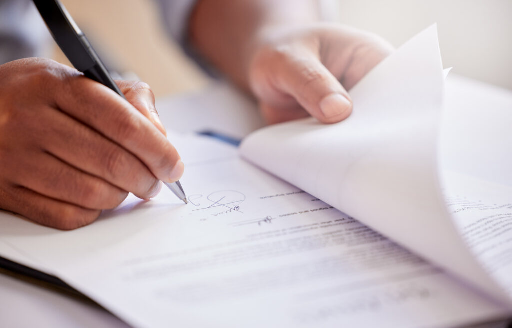 Hands, signature and writing on contract for deal at record company for music license in office. Person, legal paperwork or document for production budget, artist or sign for distribution of album AdobeStock 811990499 permits